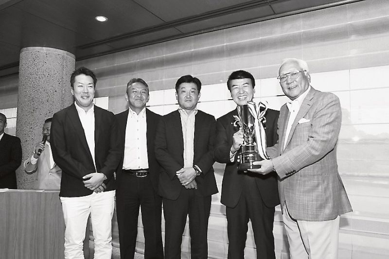 佐々野会長(右)から優勝カップを受け取るアーバネットコーポレーションのメンバー。右から2番目が服部信治同社社長