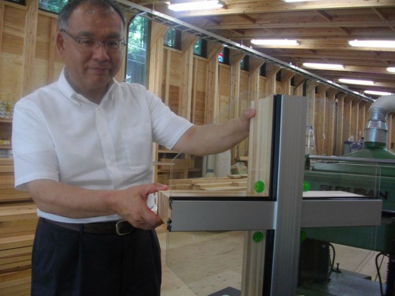 飯田信男代表。手前は、木とアルミを組み合わせた同社のオリジナルサッシ製品