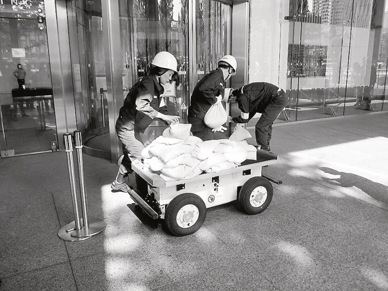 運搬ロボットで土のうを運び、ドア前に積む訓練(三菱地所)