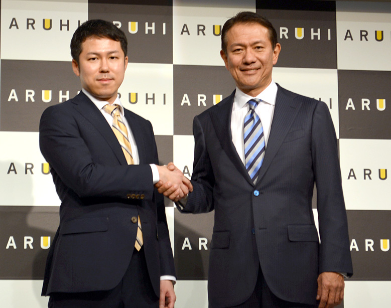 社名変更と新事業立ち上げの発表会でガッチリ握手する直海社長(左)と浜田会長