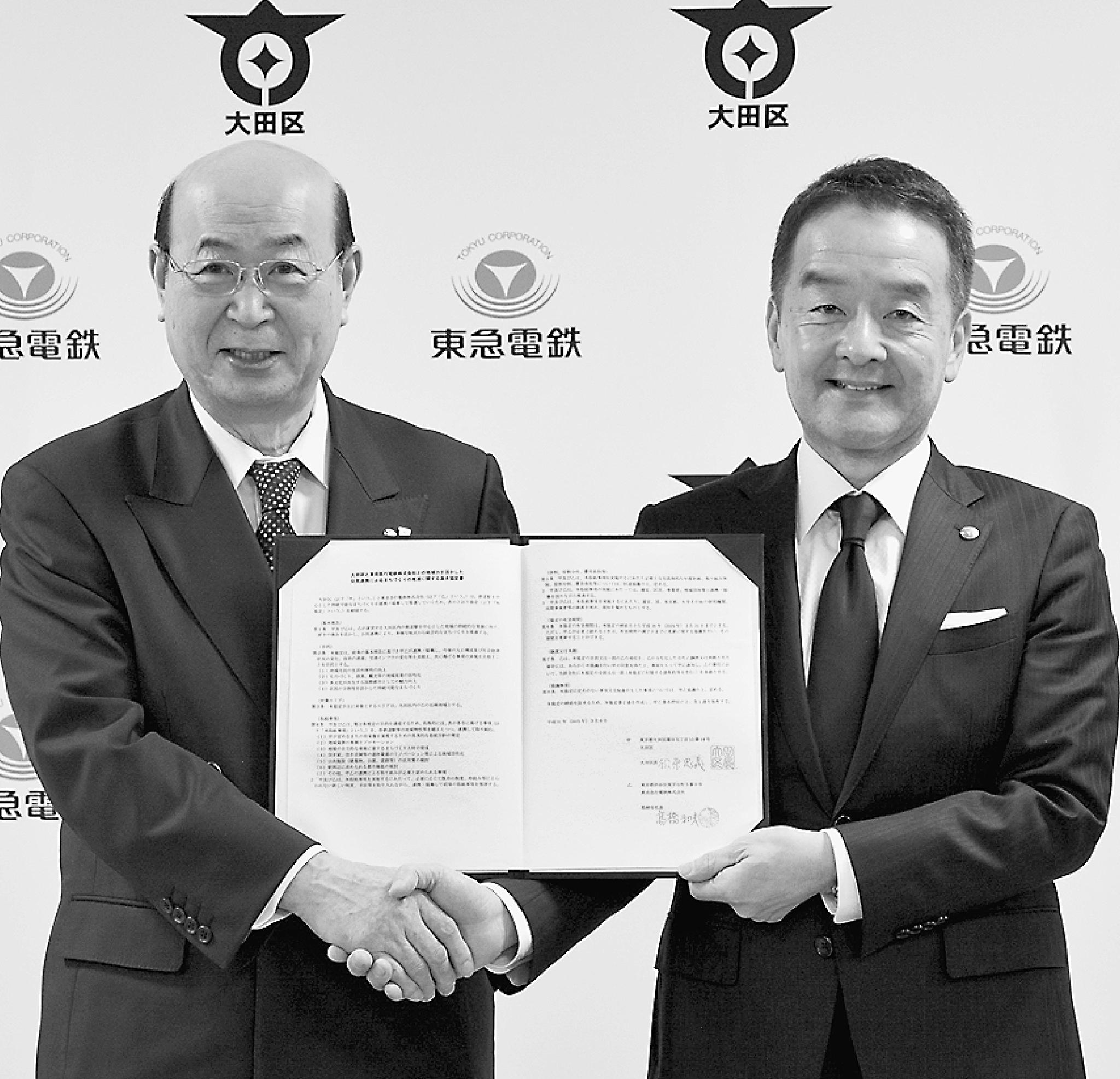 協定締結式で握手をする大田区の松原区長(左)と東急電鉄の高橋社長