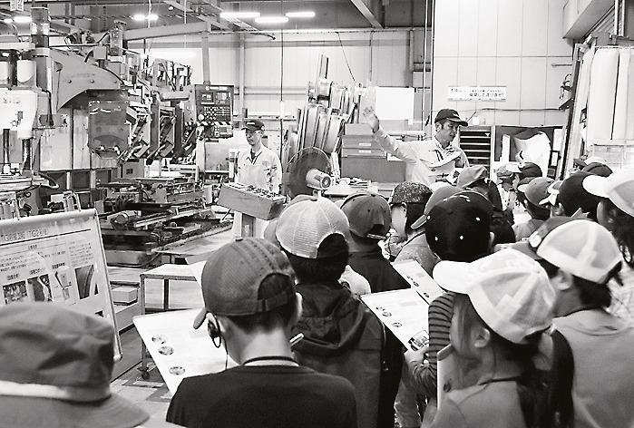 工場の製品加工過程を熱心に見学