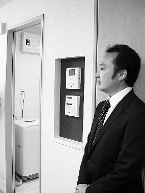 室内にある異常通報装置について説明する担当者