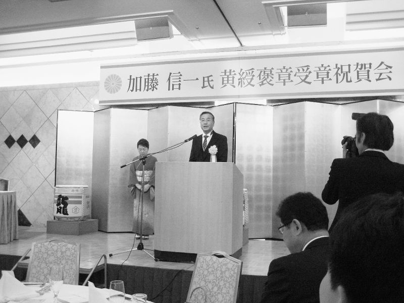 春美夫人と共に挨拶する加藤氏