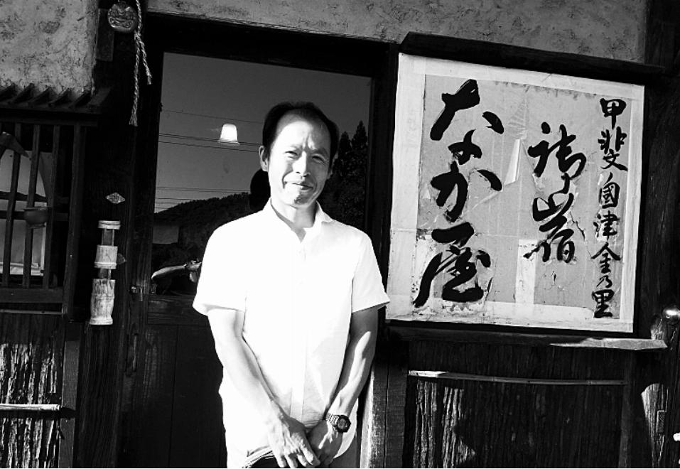 宿の前に立つ大塚さんは、畑仕事で日に焼けている