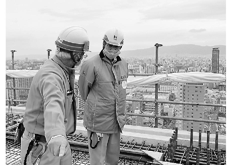 マンション最上階の建築現場を視察する辻会長(右)
