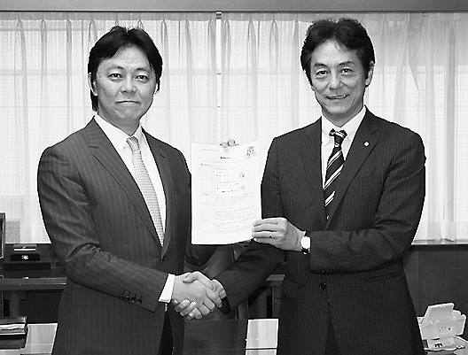 業務提携で握手する和氣理事長(右)とネクストの井上高志社長(左)