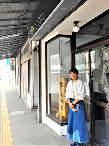 宿の前に立つ高田さん。北海道最古のアーケードが残る商店街にある
